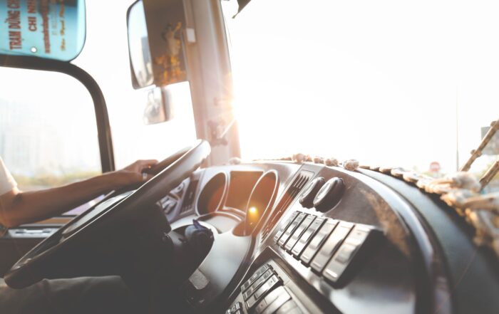 A man driving a truck, sunlight streaming through the windshield, highlighting the interior and his focused expression.