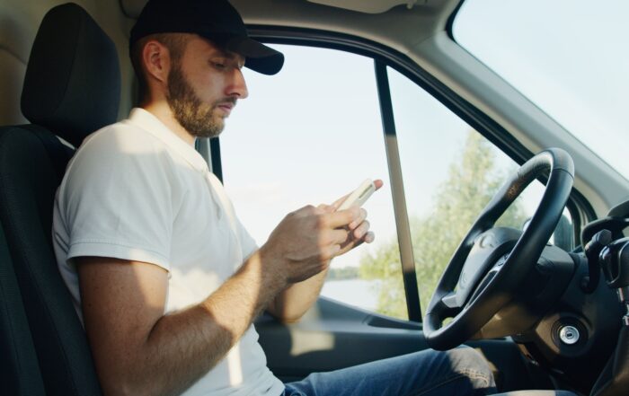 A man in a truck is using his cell phone while seated in the driver's seat.