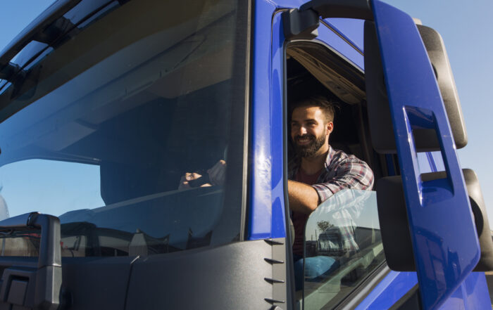 A man seated in the driver's seat of a truck, representing the profession of truck driving and its associated salary.